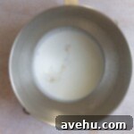 Heavy whipping cream, sugar, and vanilla in a stainless steel mixing bowl.