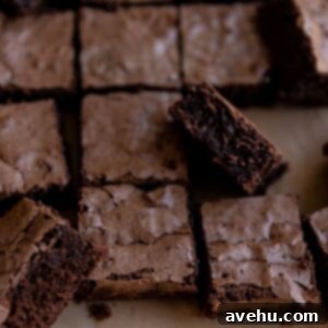 Easy & Decadent Triple Chocolate Brownies 2 A close-up of beautifully cut triple chocolate brownies with shiny, crinkled tops, showcasing their dense, fudgy interior and visible chocolate chips, ready to be enjoyed.