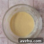 Easy and Moist One Bowl Wonder Marble Cupcakes 4 Wet ingredients in a glass bowl on a pink surface.