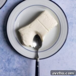 Soften Cream Cheese in Minutes 2 Soften creamed cheese on a plate with a spoon cutting into it.