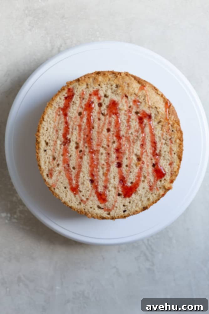 Aromatic Strawberry Basil Cake with Strawberry Buttercream 12 A perfectly leveled yellow cake layer, generously drizzled with vibrant red strawberry simple syrup, ready for frosting.
