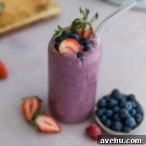 2-Minute Banana-Free Frozen Fruit Smoothie 2 A fruit smoothie in a glass cup topped with strawberries and blueberries.