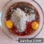 Effortless Red Velvet Cake Mix Cookies 3 Red velvet cake mix, eggs, and oil in a glass bowl.