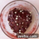 Effortless Red Velvet Cake Mix Cookies 5 Red velvet cookie dough with white chocolate chips in a glass bowl.