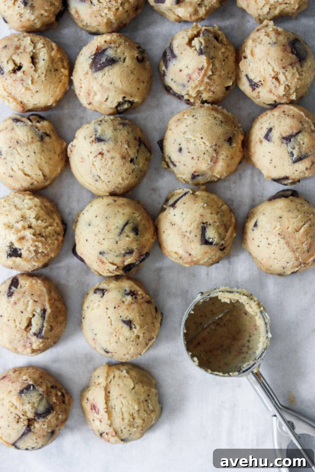 Coffee-Infused Chocolate Chip Chews 9 coffee cookie dough with with chocolate chunks lined up in balls on a sheet tray.