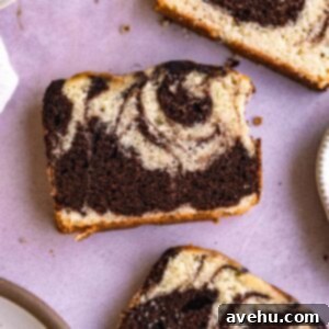 A slice of marble loaf cake next to a plate on a purple background.