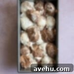 Scoops of vanilla and chocolate cake batter in a loaf pan.