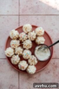 Sweet Secrets to Adorable Cupcakes 3 Mini cupcakes on a pink plate next to a bowl of vanilla frosting.