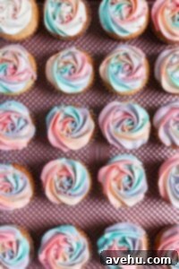 Sweet Secrets to Adorable Cupcakes 4 Multicolored cupcakes piped into rosettes on a pink tray.