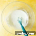 Achieve Perfect Frosting Consistency Instantly 8 A glaze icing in a glass bowl with a mini spatula inside of it.