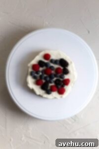 From Sunken to Superb: 5 Reasons Your Cake Sinks and 3 Simple Fixes 5 A cake layer topped with frosting and berries.