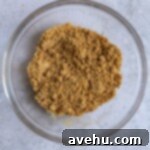 Graham cracker crumbs mixed with melted butter in a glass bowl.