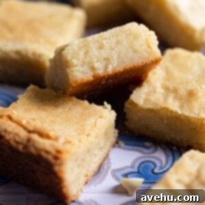 Irresistible White Chocolate Blondies 2 A white chocolate brownie on an angle to show the inside on a blue patterned surface.