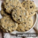Simple Chocolate Chip Cookies No Brown Sugar Required 8 Chocolate chip cookies on a plate and linen on a pink surface.