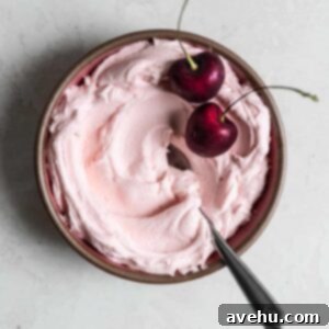 Effortless Cherry Frosting 2 Pink cherry frosting in a small bowl with 2 fresh berries on top.