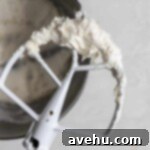 Effortless Cherry Frosting 3 A paddle attachment with white frosting on it over a mixing bowl.