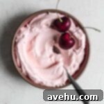 Effortless Cherry Frosting 4 Pink cherry frosting in a small bowl with 2 fresh berries on top.