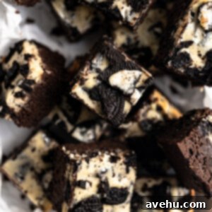 Decadent Oreo Cheesecake Brownies 2 Oreo cheesecake brownies cut and layered on top of each other on parchment paper.