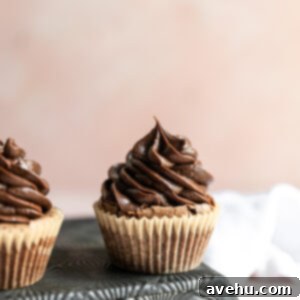 Instant Indulgence Brownie Bites 2 A brownie cupcake with chocolate fudge frosting on a tin with a pink background.
