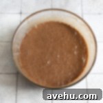 Handcrafted Fudgy Chocolate Brownie Masterpiece 5 Thick, glossy chocolate brownie cake batter in a clear glass mixing bowl, showcasing its rich texture before being poured into a pan.