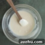 A maple glaze in a glass bowl with a spatula.