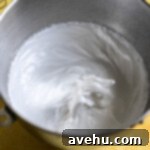 Velvet Zest Lemon Curd Cake 11 Meringue in a stainless steel bowl.