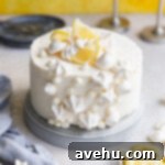 Velvet Zest Lemon Curd Cake 15 A lemon curd cake with white decorations on a gray surface next to a blue linen.