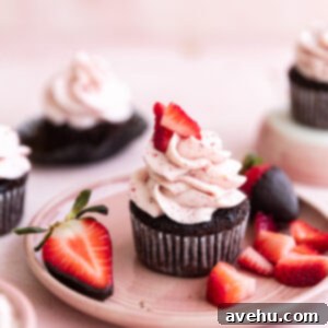 Heavenly Chocolate Strawberry Cupcakes 2 Chocolate strawberry cupcakes topped with fresh berries on a pink plate.