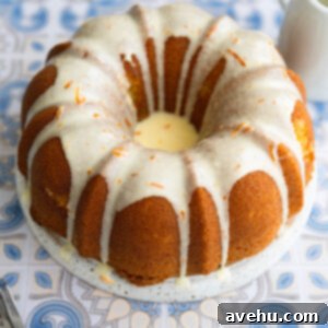 2 Minute Zesty Orange Glaze 2 A bundt cake with orange glaze poured over it on a decorative blue surface.