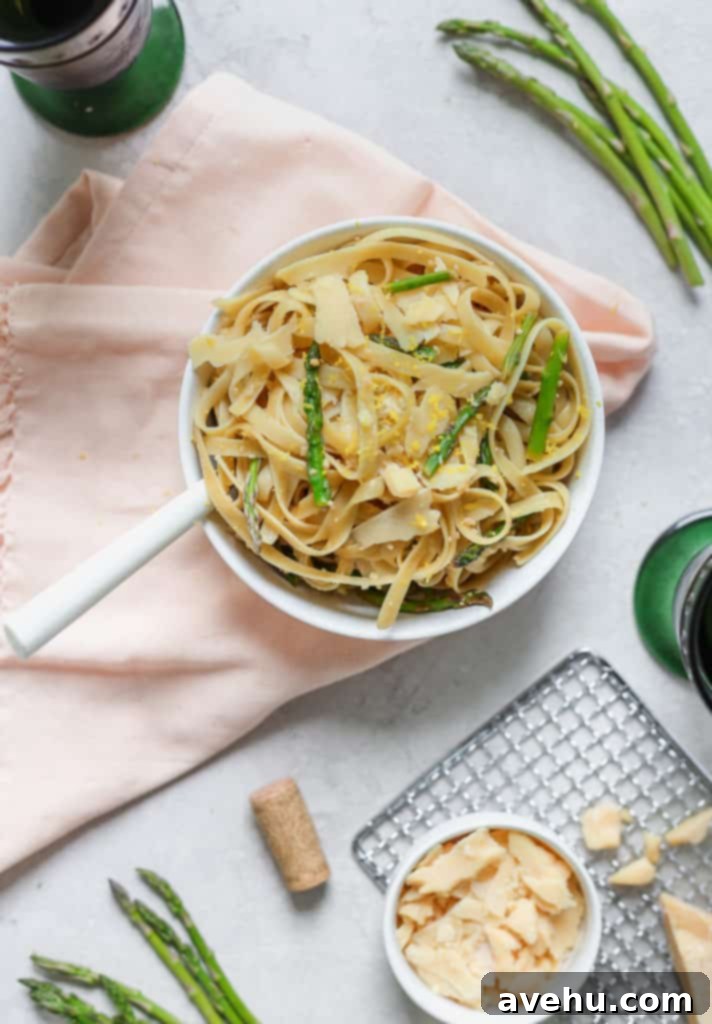 Asparagus and Lemon Fettuccine with Shaved Parmesan 4 Fettuccine pasta with asparagus and lemon served in a white bowl over a pink napkin with parmesan cheese on the side.