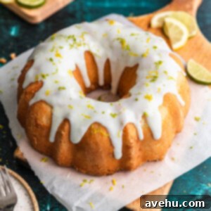 A 7 up bundt cake on a pieces of parchment paper and a wooden cutting board with lemon and lime slices next to it.