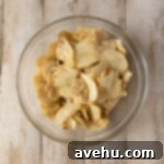 Effortless Cinnamon Roll Apple Pie 4 Sliced apples and cinnamon in a bowl.