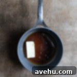 Buttery Flaky Apple Dumplings 3 A saucepan filled with sauce ingredients including melted butter and brown sugar, simmering on the stove.