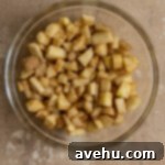 Velvet Apple Pie Cheesecake 3 Diced spiced apples in a bowl.