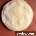 Crisp Puff Pastry Apple Dream 6 An unbaked puff pastry apple pie on a red surface, with edges crimped by a fork and slits cut on top.