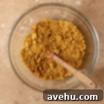 Effortless Graham Cracker Apple Pie 3 Graham cracker crumbs mixed with melted butter and sugar in a bowl, showing a wet sand texture.