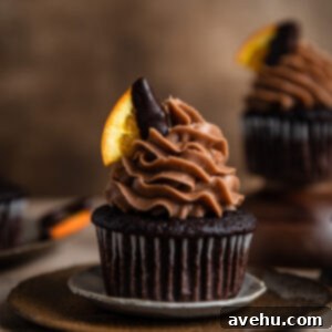 Effortless Chocolate Orange Cupcakes 2 A chocolate cupcake topped with chocolate frosting and garnished with a chocolate covered orange slice.