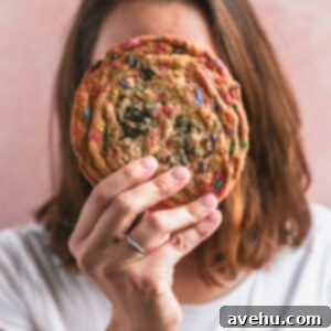 Big, Chewy Funfetti Party Cookies 2 A person holding a giant funfetti cookie up to their face, showcasing the large size and delightful sprinkles.