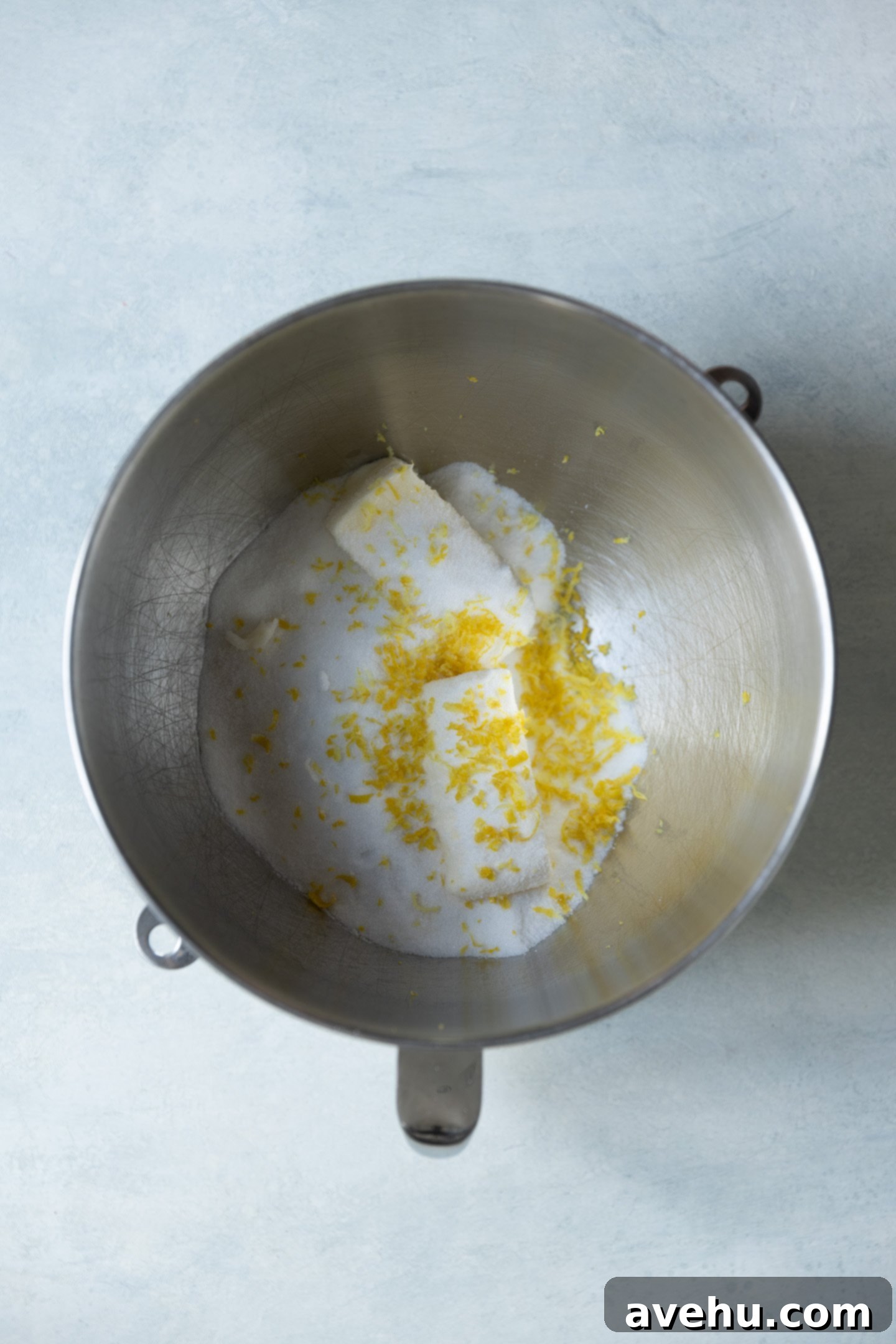 Bright & Zesty Lemon Blueberry Cupcakes 4 Fresh lemon zest, softened butter, and granulated sugar ready to be creamed in a stainless steel mixing bowl, showing the vibrant yellow of the zest.