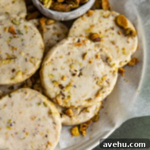 Buttery Pistachio Shortbread Logs 13 A pistachio shortbread cookies stacked on others in a bowl.