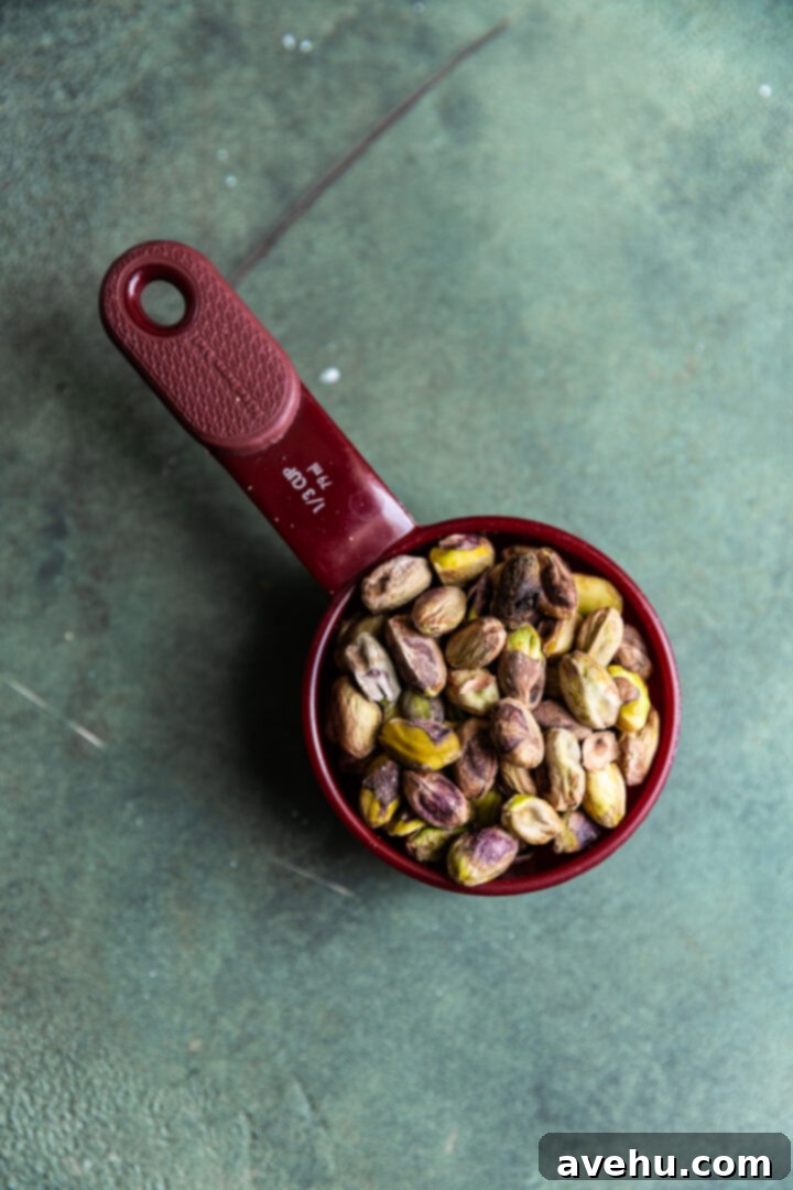 Buttery Pistachio Shortbread Logs 3 Shelled pistachios neatly arranged in a 1/3 cup measuring cup, ready for chopping.