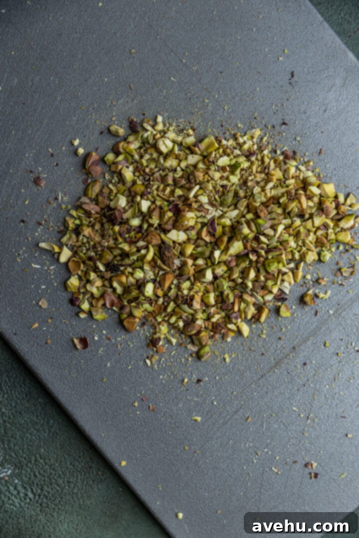 Buttery Pistachio Shortbread Logs 4 Finely chopped pistachios scattered on a wooden cutting board, ready to be incorporated into the dough.