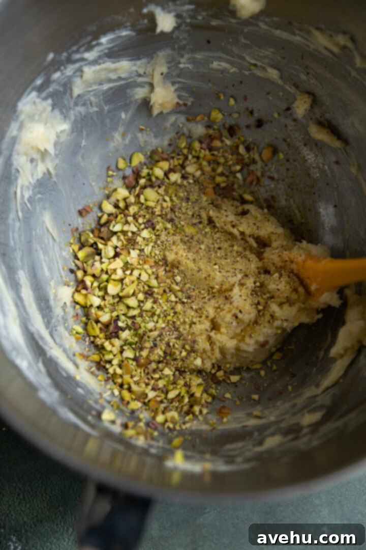 Buttery Pistachio Shortbread Logs 6 Chopped pistachios being added to the creamed butter and sugar mixture in a mixing bowl, prior to adding flour.
