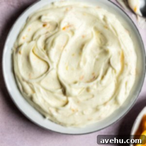Orange cream cheese frosting swirled in a bowl.