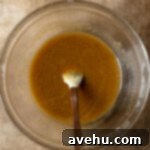 Quick 25-Minute Double Chocolate Chip Cookies 2 Melted butter, brown sugar, and white sugar stirred in a glass mixing bowl.