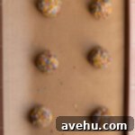 Birthday cake cookie dough balls lined on a baking sheet.