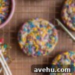 A colorful sprinkle cookie on a cooling rack next to candles and matches.