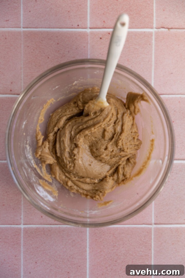 Quick 30 Minute Birthday Cake Cookies 4 Unfinished cookie batter in a glass bowl with a spatula, showcasing a simple, easy-to-mix consistency.