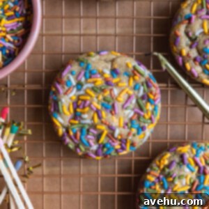 A colorful sprinkle cookie on a cooling rack next to candles and matches.