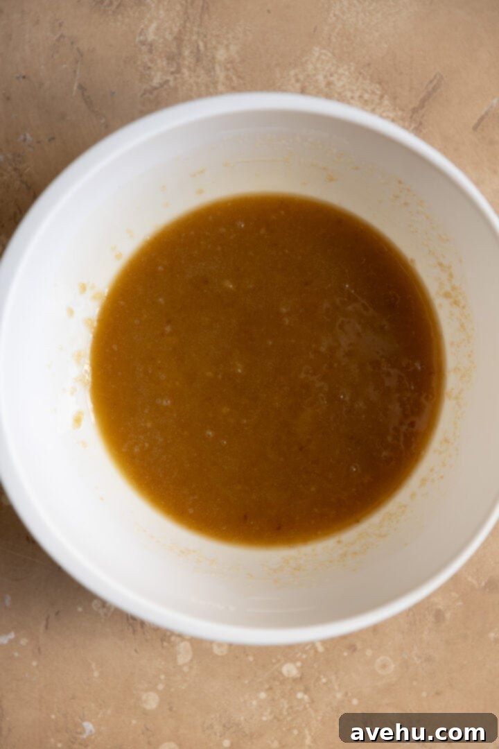 Melted butter, rich brown sugar, and sparkling white sugar are perfectly mixed together in a bowl, ready for the next steps.